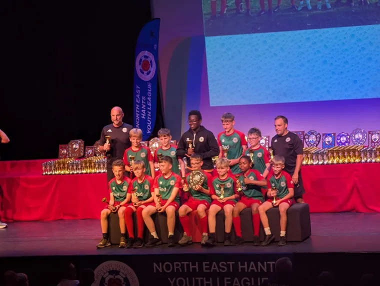 Ash United players and coaches with a full table of trophies at the league awards evening