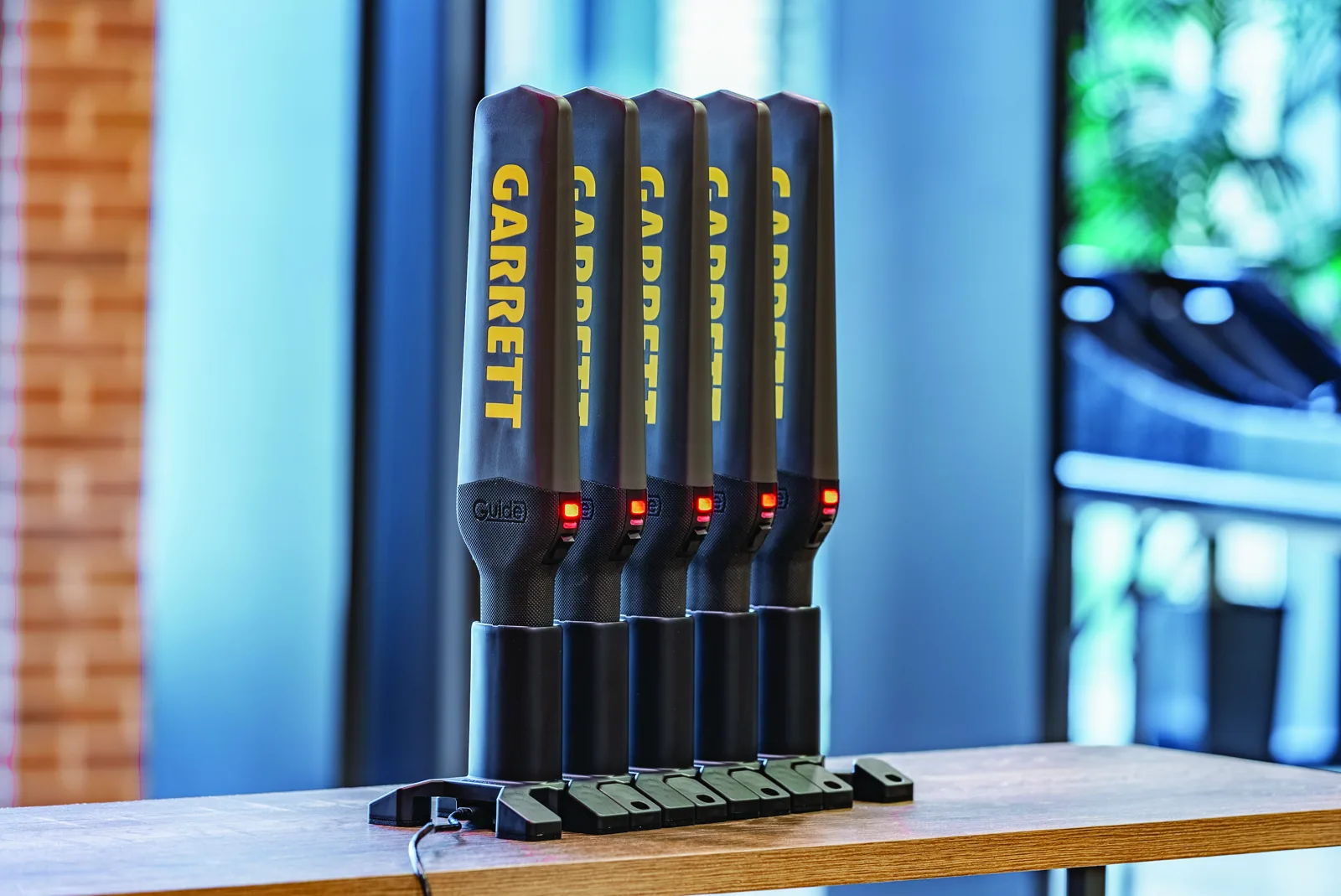 Five Garrett Guide handheld metal detectors charging side by side in a modular docking station
