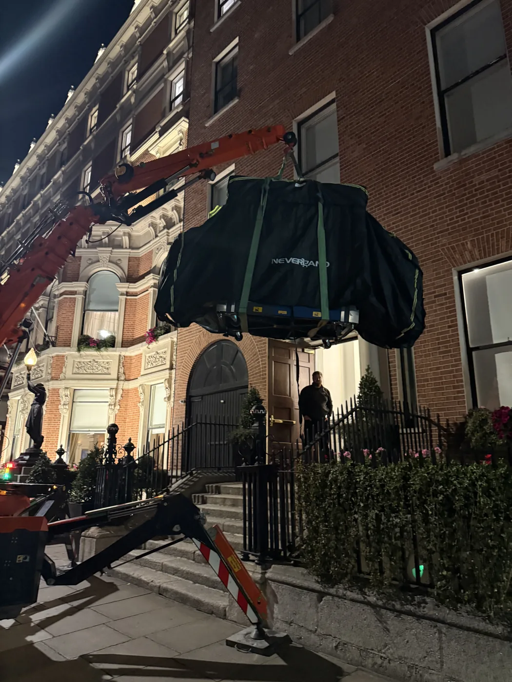 Spider crane lifting a wrapped X-ray machine over railings into a London building at night during a RedteQ machine move